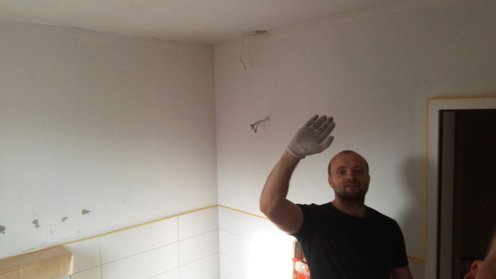 Malermeister beim Streichen einer Decke im Innenraum