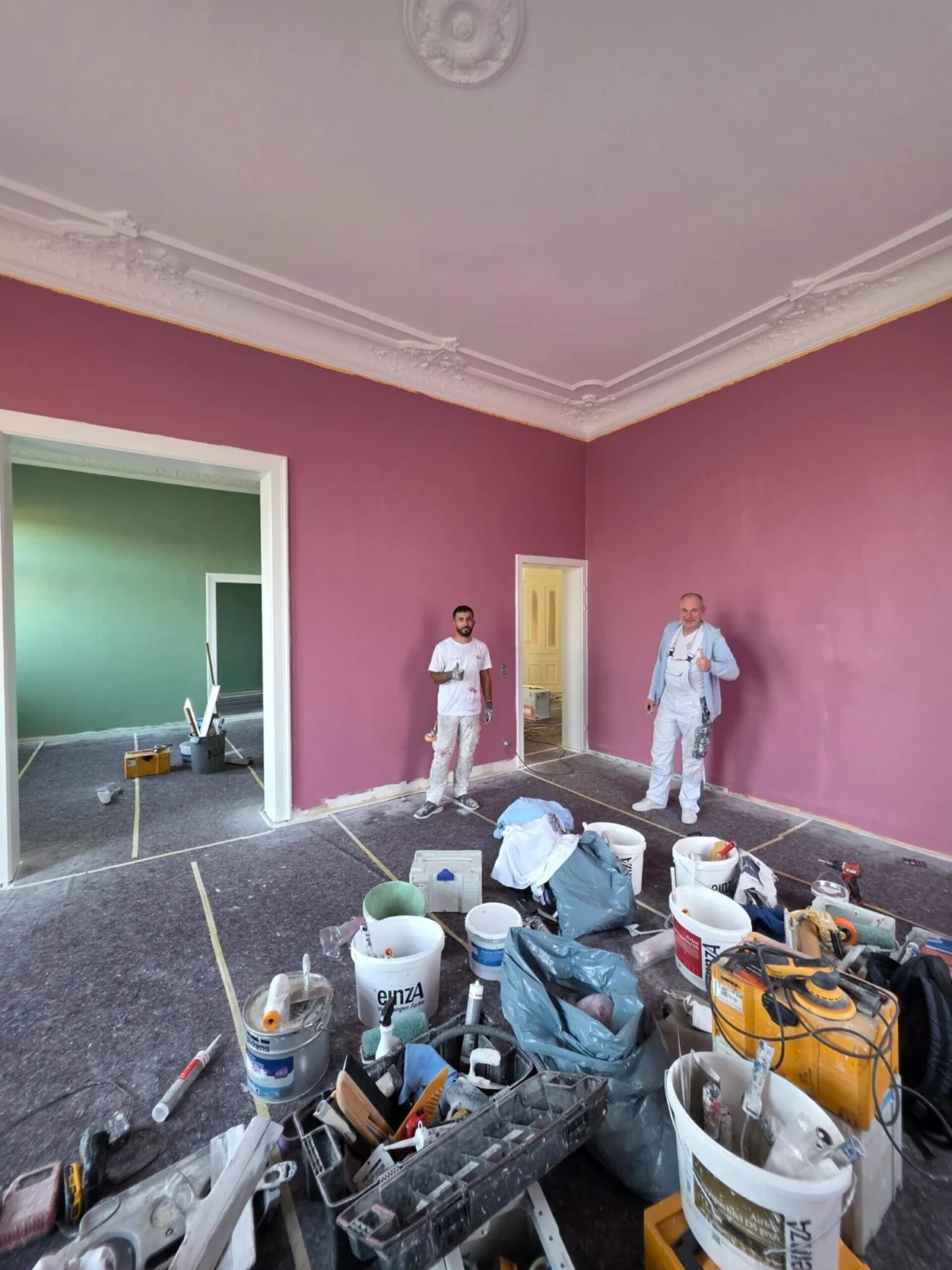 Malerarbeiten in rotem Wohnraum mit Arbeitsmaterial