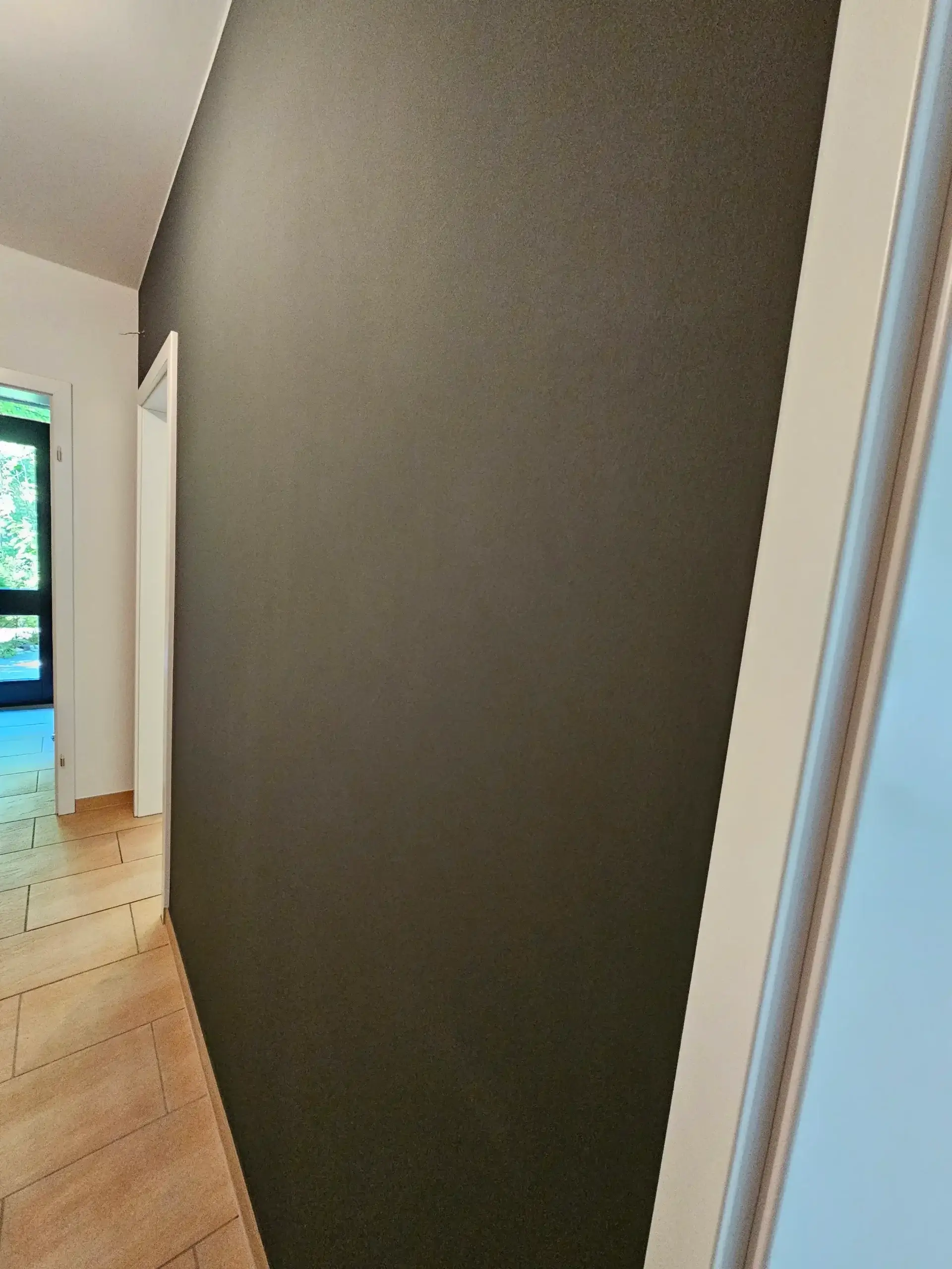 Dunkel gestrichene Akzentwand im Flurbereich nach professionellen Malerarbeiten in Bielefeld